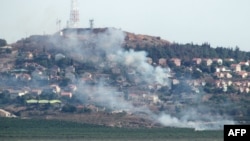 На фотографии, сделанной на юге Ливана, видны клубы дыма в северном израильском городе Метулла от ракет, запущенных со стороны Ливана 26 июня.