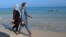 Women walk on a beach wearing burkinis.