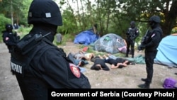 Jedna od fotografija migranata koji leže na zemlji, sa rukama iza glava i šatorima u pozadini, dok iznad njih stoje maskirani policajci sa oružjem. Fotografije je u nedelju, 4. jula, uz inoformaciju o pronalaženju ilegalnog kampa, medijima prosledila srpska policija.