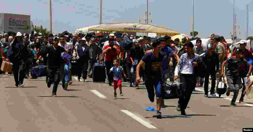 Turkey -- Syrians, who say they are returning to Syria ahead of the Eid al-Fitr, carry their belongings as they walk to the Turkish Cilvegozu border gate, located opposite of Syrian crossing point Bab al-Hawa in Reyhanli, in Hatay province, June 15, 2017