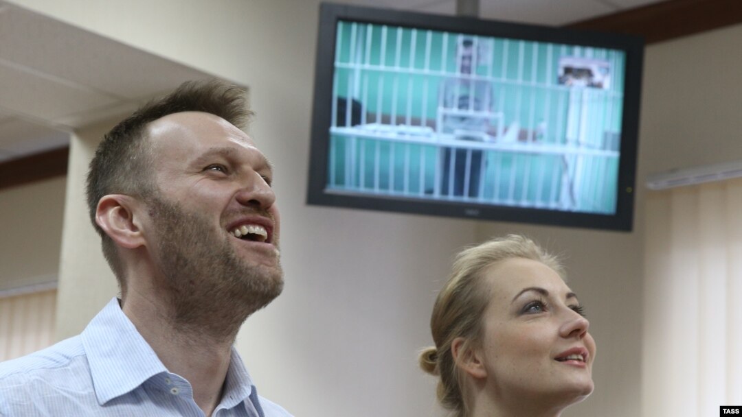 Russian opposition leader Aleksei Navalny and his wife, Yulia, laugh during a video-link with his brother Oleg, shown on a screen, in a court in Moscow on February 17.