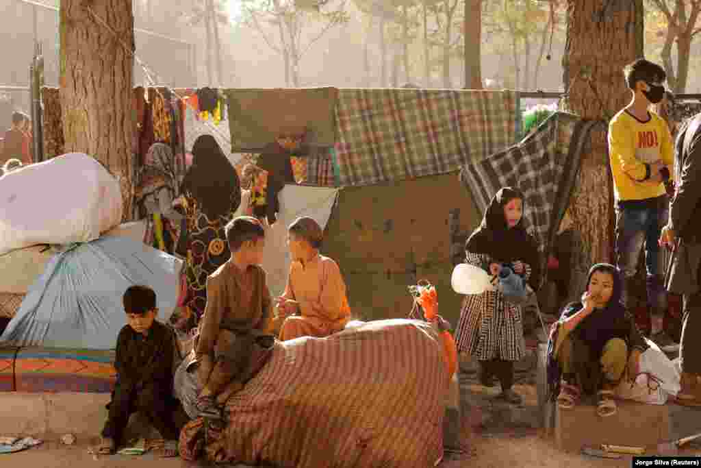 Afghan families, who are among displaced people fleeing the violence in their provinces, sit with their belongings as they prepare to return to their provinces, at a makeshift shelter at Shahr-e Naw park, in Kabul, Afghanistan October 4, 2021.&nbsp;