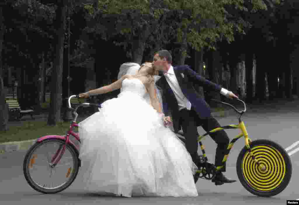 Yelena Babkini (left) and her husband, Boris, kiss as they ride through Gorky Park on bicycles after having been married earlier in the day in Moscow. (Reuters/Gary Hershorn)