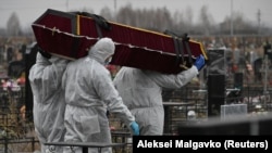 Sírásók cipelik egy Covid-gyanús elhunyt koporsóját Oroszországban. 2020. november. 20.