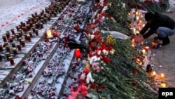 A man lights candles in front of the Lame Horse nightclub after a fire broke out in Perm in December 2009, killing 156 people.