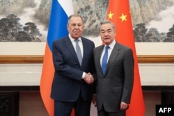 Russian Foreign Minister Sergei Lavrov and Chinese Foreign Minister Wang Yi shake hands during a meeting in Beijing on April 14.