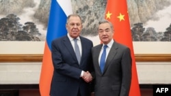 Russian Foreign Minister Sergei Lavrov and his Chinese counterpart Wang Yi shake hands during a meeting in Beijing on April 14.