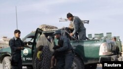 Afghan policemen rescue civilians from the site of an attack in Kandahar on October 27.