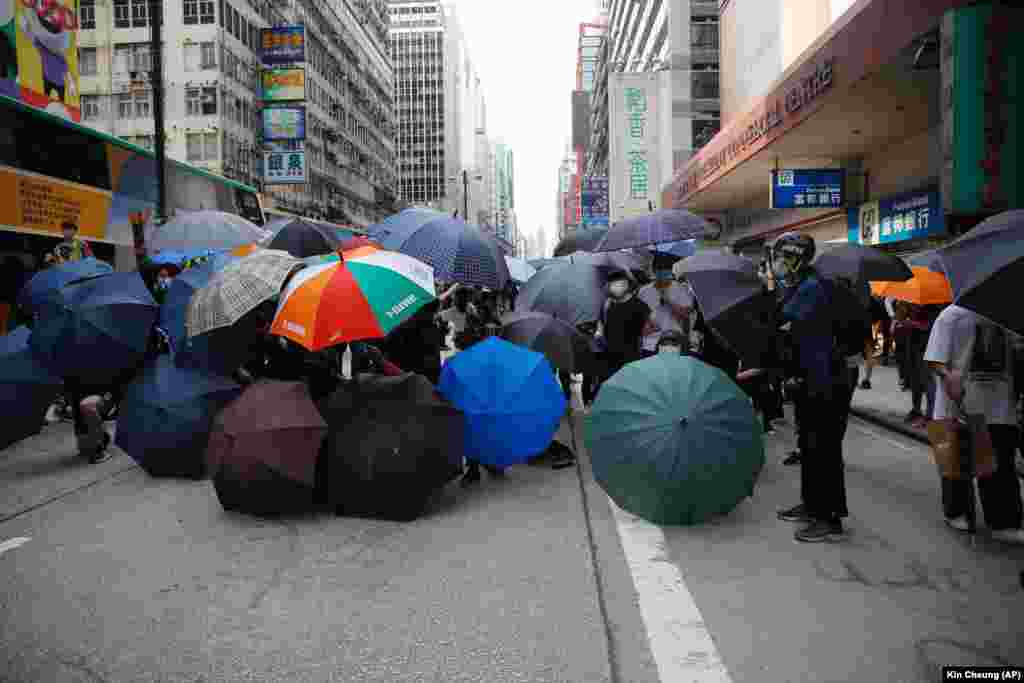 Protestatari folosesc umbrele ca scuturi, scandând lozinci pro-democrație, dar și insulte la adresa poliției din Hong Kong, înaintea dezbaterilor din legislativul local, 27 mai 2020