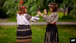 Women wearing traditional Romanian blouses known as ia or ie (pronounced "ee-yeh") use mobile phones to check their outfits during an event celebrating rural national costumes in Bucharest last month. 