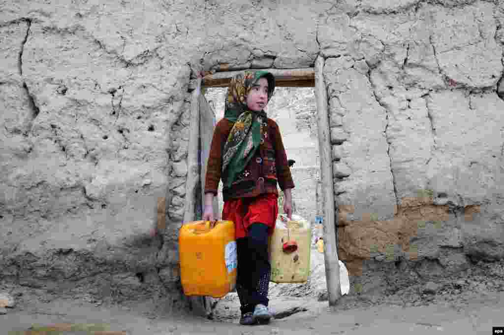 A young Afghan girl carries water cans on the outskirts of Mazar-e Sharif. (epa/Sayed Mustafa)