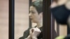 Belarusian opposition politician Maryya Kalesnikava, charged with extremism and trying to seize power illegally, forms a heart shape in handcuffs inside a defendants' cage as she attends a court hearing in Minsk in September 2021.