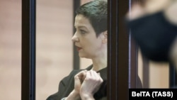 Belarusian opposition politician Maryya Kalesnikava, charged with extremism and trying to seize power illegally, forms a heart shape in handcuffs inside a defendants' cage as she attends a court hearing in Minsk in September 2021.