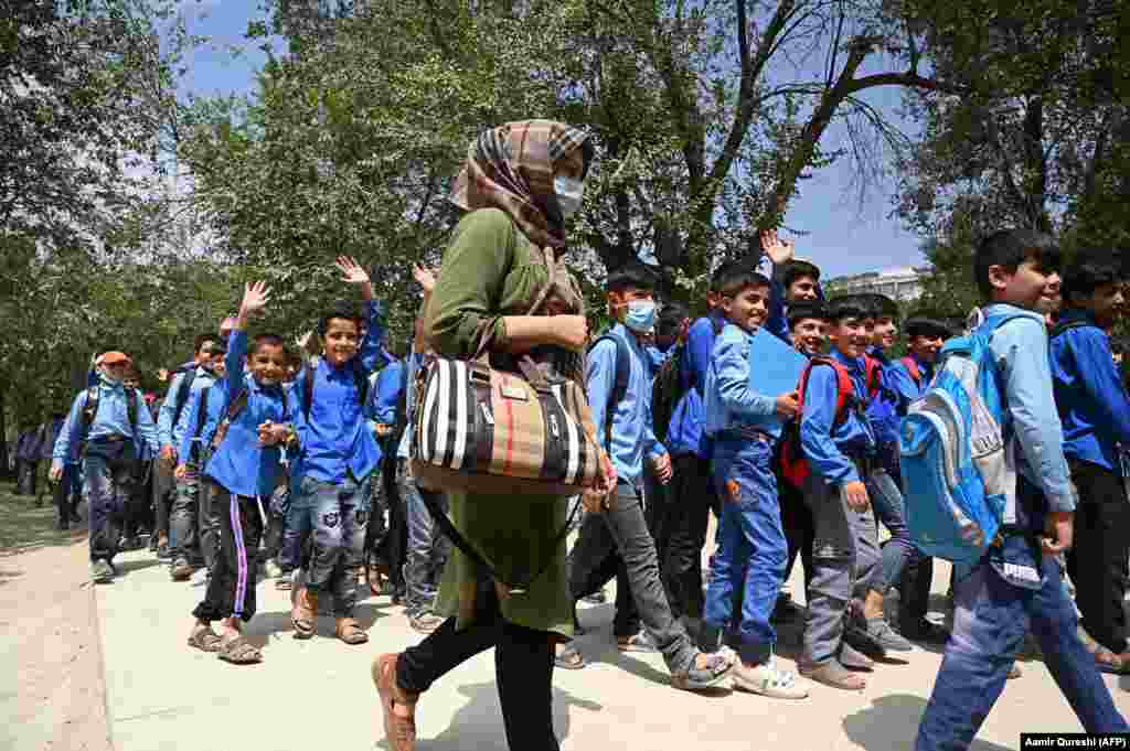 Despite the risks, some schools have reopened. These students and their teacher at a Kabul middle school were photographed on their way to class on August 30. &nbsp;