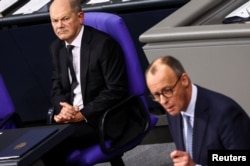 Olaf Scholz (stânga) privește cu furie înspre liderul creștin-democraților, Friedrich Merz, în timpul dezbaterii de miercuri care a dus la aprobarea unei moțiuni cu ajutorul extremiștilor.