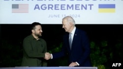 Președintele ucrainean Volodimir Zelenski (stânga) și președintele american Joe Biden semnează un acord bilateral de securitate, 13 iunie 2024, la Summitul G7 din Italia.