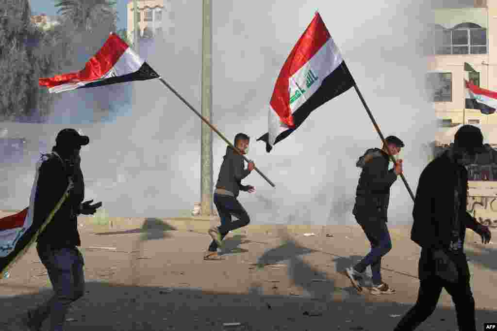Iraq paramilitaries and their supporters react after tear gas is fired upon them outside the U.S. Embassy in the Iraqi capital, Baghdad, on January 1. (AFP/Ahmad Al-Rubaye)