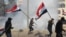 U.S. forces (unseen) fire teargas canisters at supporters and members of the Hashed al-Shaabi paramilitary force during a demonstration outside the US embassy in the Iraqi capital Baghdad on January 1, 2020.