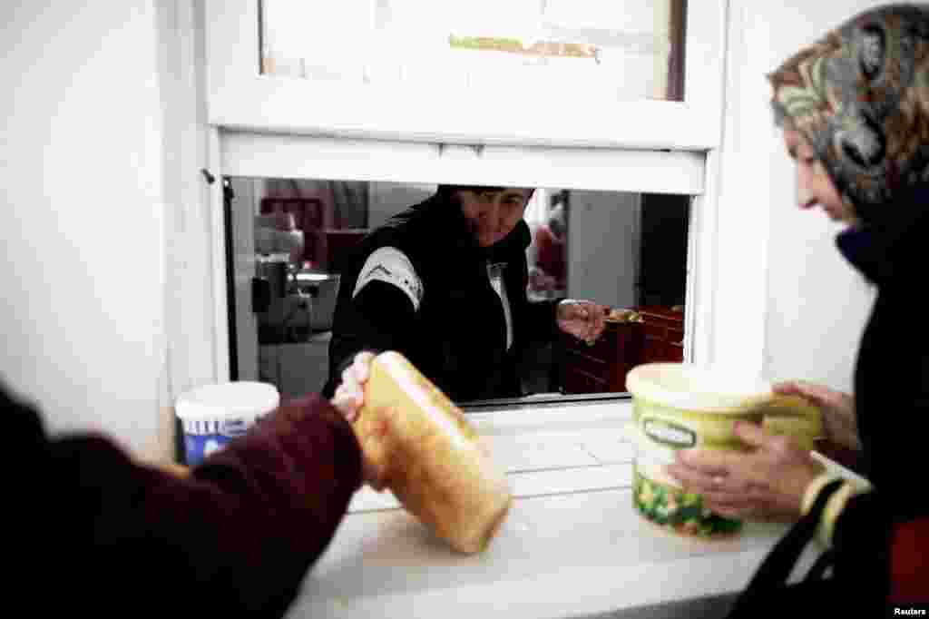 People receive food at one of Mostar&#39;s two soup kitchens -- one of the services threatened by the city&#39;s failure to approve the 2013 budget. 