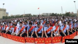 Police wearing sashes hold placards during a ceremony to award those who the authorities say participated in "the crackdown of violence and terrorists activities" in China's Xinjiang Uyghur Autonomous Region.