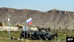 Russian peacekeepers stand next to an armored vehicle at a checkpoint in Nagorno-Karabakh on October 7, 2023.