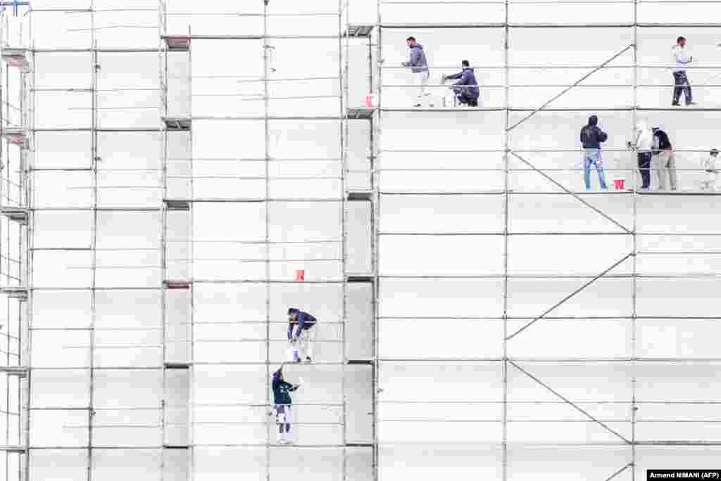 Construction workers paint a building at a site near Pristina. (AFP/Armend Nimani)