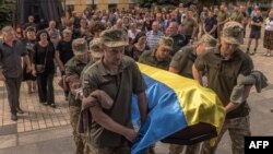 Soldații ucraineni purtând un sicriu, acoperit cu steagul național, al militarului ucrainean Iuri Iurcenko, ucis în luptele din regiunea Lugansk, în timpul slujbei funerare care a avut loc la Kiev, pe 3 august.