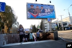 People walk passed a billboard of a United Russia party poster that reads: "For Donbas, where you want to live!" prior to local elections in Donetsk, the capital of the Ukraine's Donetsk region, on September 7.