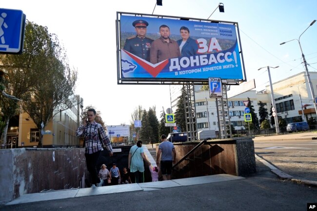 People walk passed a billboard of a United Russia party poster that reads: "For Donbas, where you want to live!" prior to local elections in Donetsk, the capital of the Ukraine's Donetsk region, on September 7.