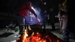 Residents of an apartment block gather on the street for a communal barbecue on January 18 after Russian strikes on Kyiv's energy grid cut power to many parts of the Ukrainian capital.