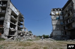 Чоловік між зруйнованими будівлями в Ізюмі Харківської області, 27 липня 2023 року