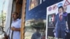 A Libyan rebel stands by a shop window decorated with a portrait of Muammar Qaddafi with his son Saif al-Islam on his shoulders in Tripoli.