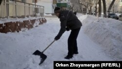 Дворник расчищает тротуар после снегопада в Астане. Иллюстративное фото.