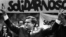 Poland -- Solidarity founding leader Lech Walesa shows v-sign in front of Solidarity poster during his presidential campaign in Plock, May 7, 1989