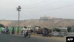 Місцеві мешканці дивляться на готель, що зазнав нападу (вдалині на пагорбі), Ґвадар, 11 травня 2019 року