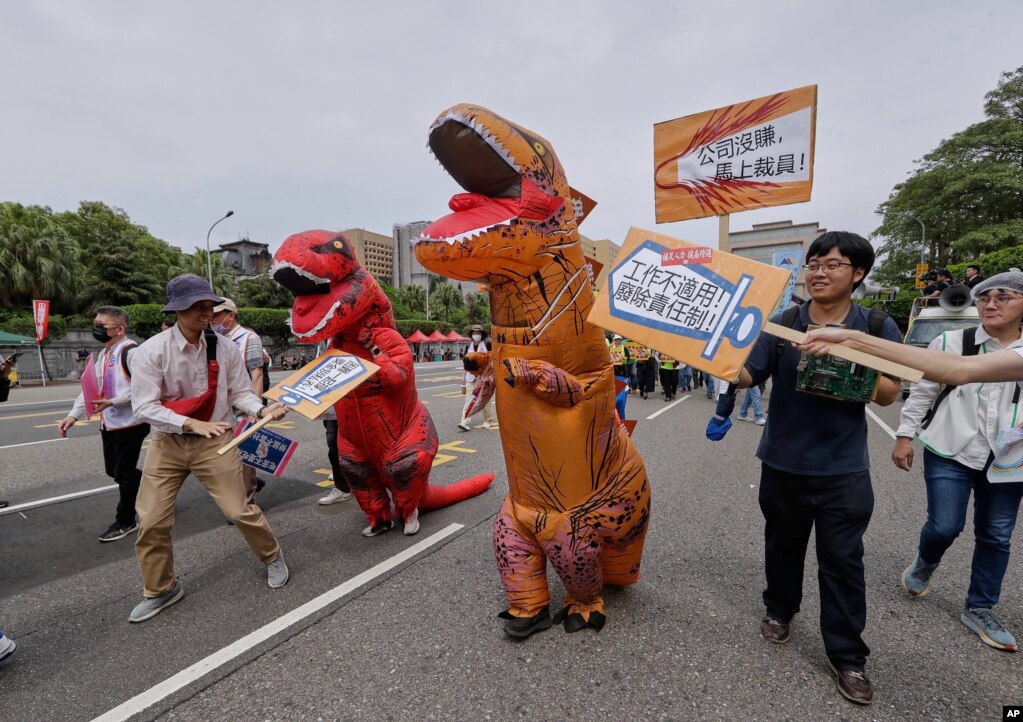 Punëtorë tajvanezë, të veshur si dinosaurë, duke protestuar në Tajpei.