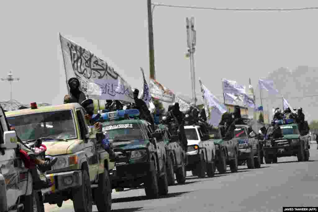 Taliban fighters atop vehicles with Taliban flags parade along a road in Kandahar on September 1 to celebrate after the United States pulled all its troops out of Afghanistan following the Taliban&#39;s military takeover of the country.