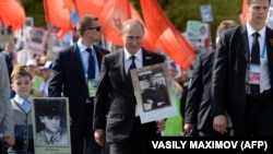 Russian President Vladimir Putin (center) carries a portrait of his father as he takes part in the Immortal Regiment march during the Victory Day celebrations in Moscow on May 9, 2015.