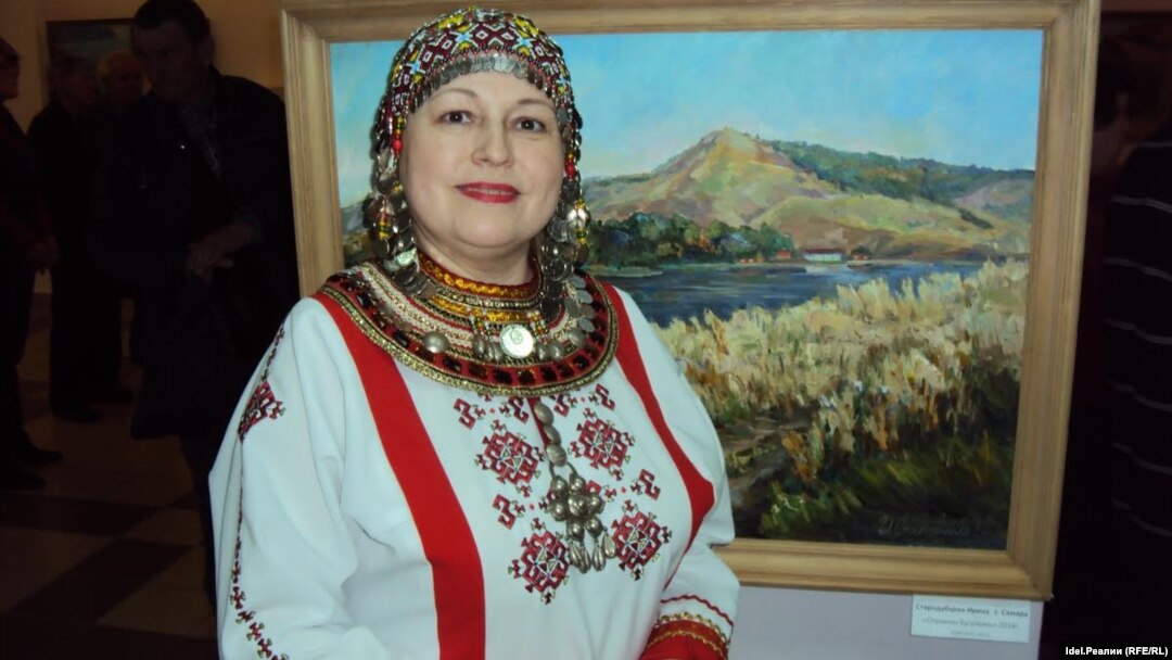 Руководитель чувашского ансамбля "Салам" из Казани, журналистка Светлана Садыкова на фоне пейзажа Ирины Стародубцевой (Самара) "Окраины Бугульмы"