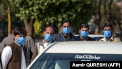 Drivers who work for a Pakistan-based Chinese company look on as they wear protective face masks before their temperatures are checked in Islamabad on January 30.