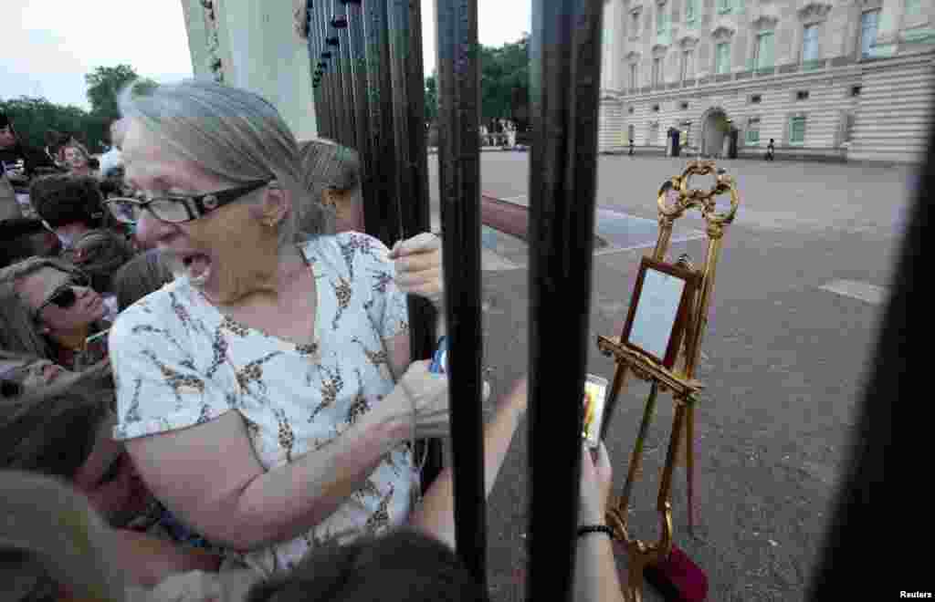 Crowds of people try to read a notice formally announcing the birth of a son to Britain&#39;s Prince William and Catherine, the duchess of Cambridge, placed in the forecourt of Buckingham Palace in central London.