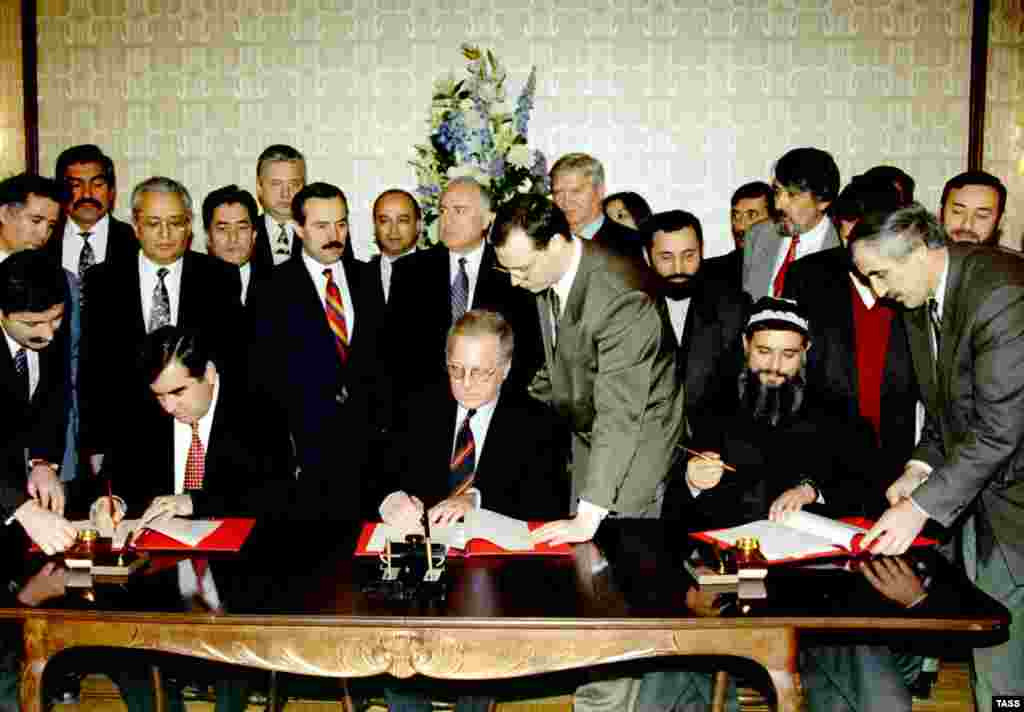 Tajik President Emomali Rahmon (left) and the&nbsp;leader of the Islamic opposition, Said Abdullo Nuri (right), during a ceremony to mark the signing of a peace agreement in the presence of Russian Prime Minister Viktor Chernomyrdin on December 23, 1996. In the center is the UN secretary-general&#39;s special envoy, Herd Merrem.