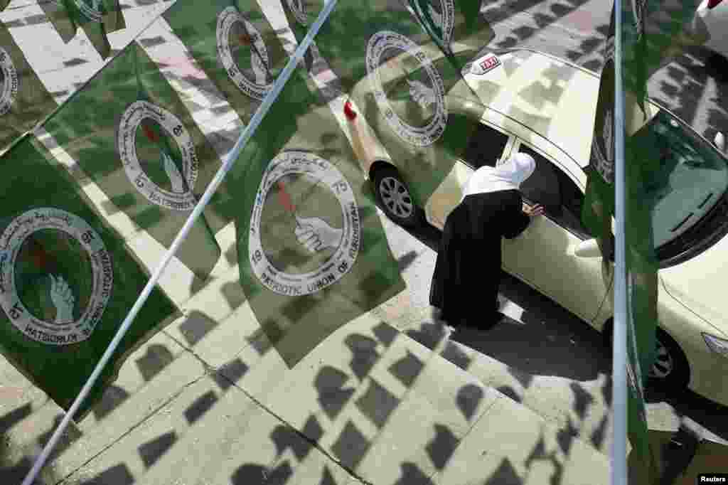 A woman hails a taxi while standing under Patriotic Union of Kurdistan (PUK) logos before parliamentary elections in Sulaimaniya, Iraq. (Reuters/Jacob Russell)