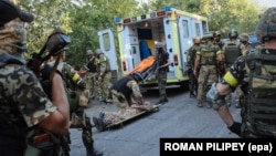 Українські бійці рятують товариша, пораненого під час бою з російськими гібридними силами поблизу Іловайська, 10 серпня 2014 року