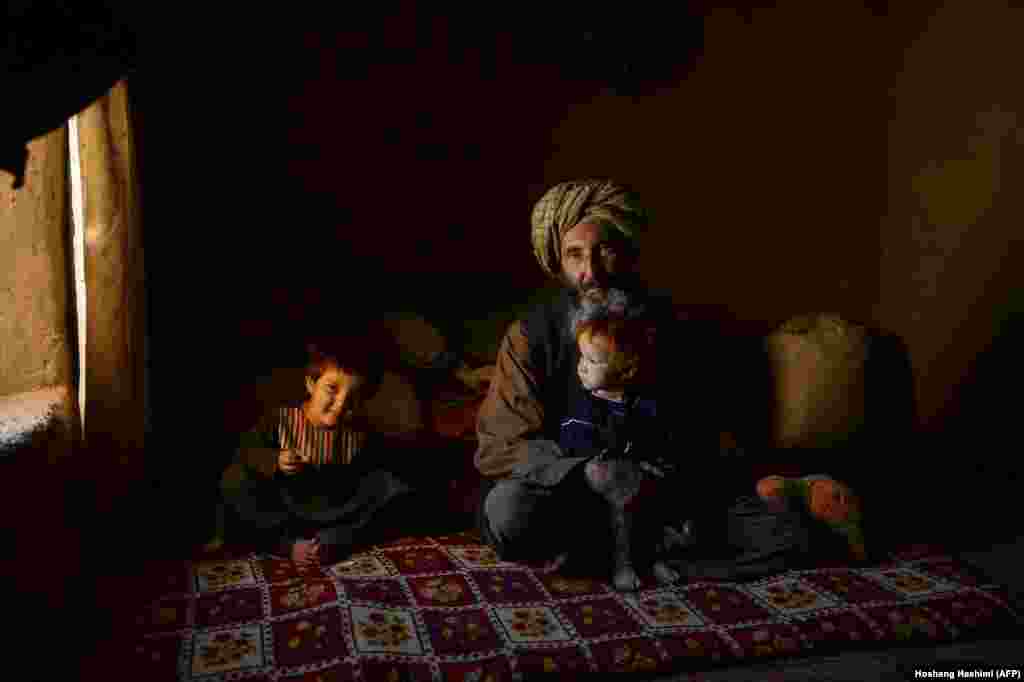 An internally displaced man sits with his children at a temporary home in a refugee camp on the outskirts of Herat, Afghanistan. (AFP/Hoshang Hashimi)