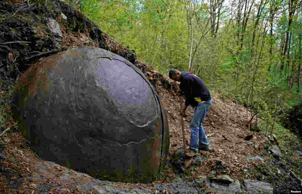 Suad Keserovic cleans a stone ball in the village of Podubravlje near Zavidovici, Bosnia-Herzegovina. Keserovic claims that the stone sphere is 3.30 meters in diameter and weighs an estimated 35 tons. Controversial archaeologist Semir Osmanagic asserts that it is the world&#39;s largest man-made sphere and may be 1,500 years old, but others cast doubt on this claim. Hundreds of tourists from around the world have visited the stone. (Reuters/Dado Ruvic)