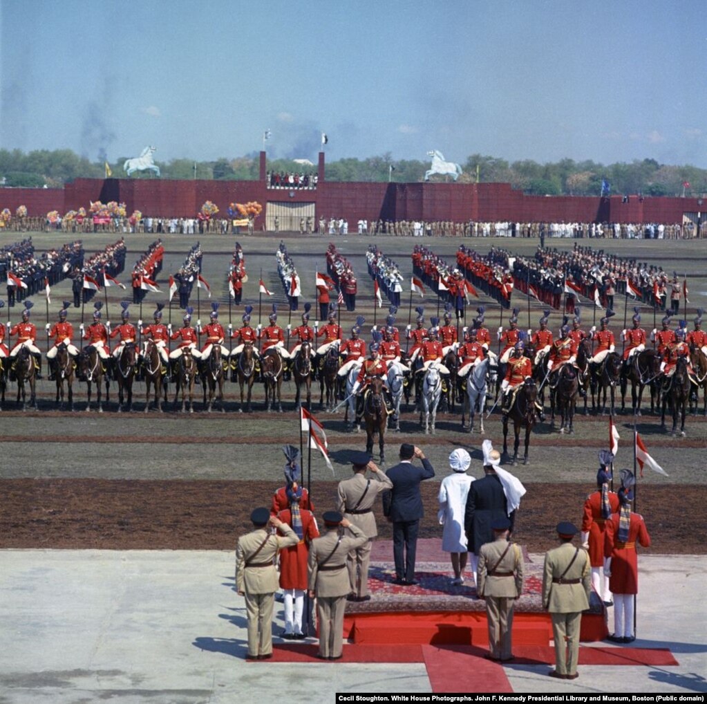 The first lady, in white coat and hat, watches the parade at a horse and cattle fair in Lahore on her first full day in Pakistan.