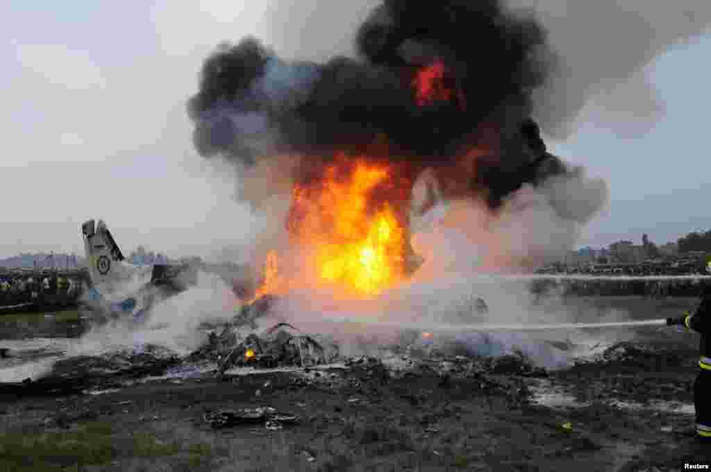 Rescue workers douse a Dornier aircraft that caught fire after it crashed in Kathmandu, Nepal. All 19 people on board died in the crash on September 28. (REUTERS)