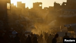 Njerëz duke ecur mbi gërmadhat e një tregu pas një sulmi izraelit në Han Junis, në jug të Rripit të Gazës, 30 qershor 2024.