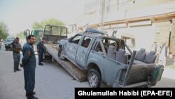 FILE: Afghan police officials inspect a damage vehicle, after it hit a bomb blast, in Jalalabad, the capital of Nangahar Province in April.